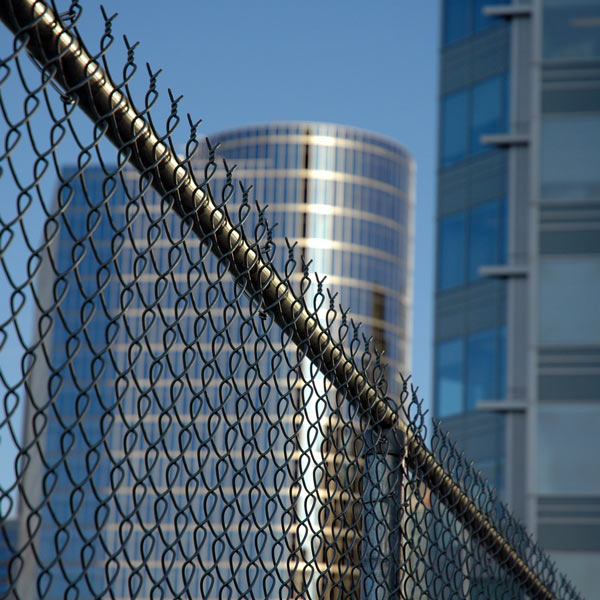 chain link fence with large buildings in the background